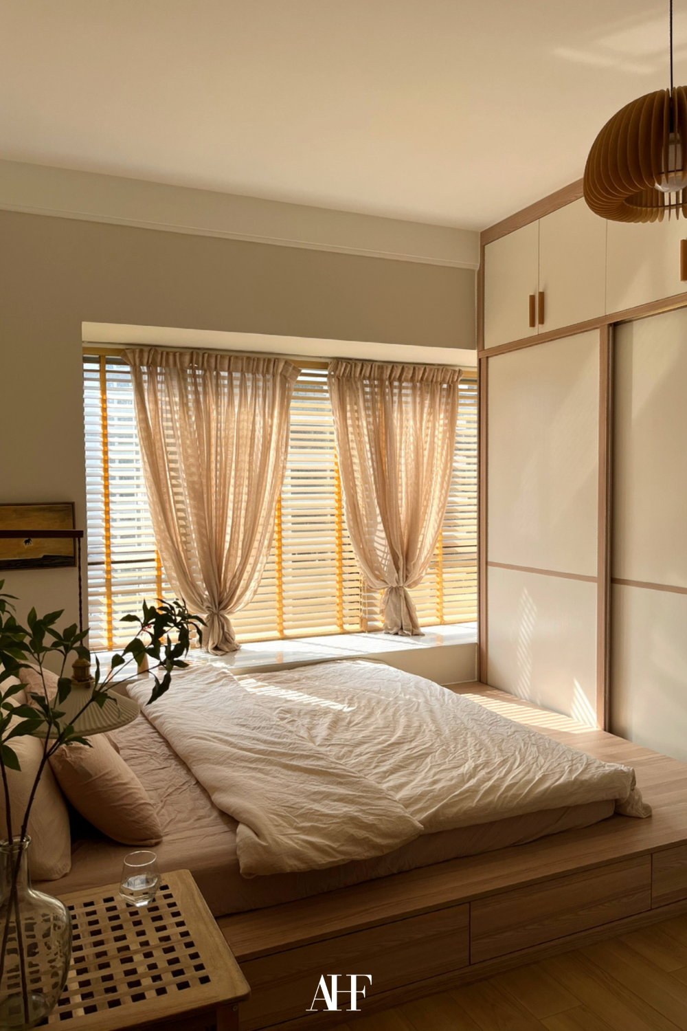 Very beautiful lighting. Japandi bedroom ideas with a wooden framed bed, wooden wardrobes and a large plant and windows. 