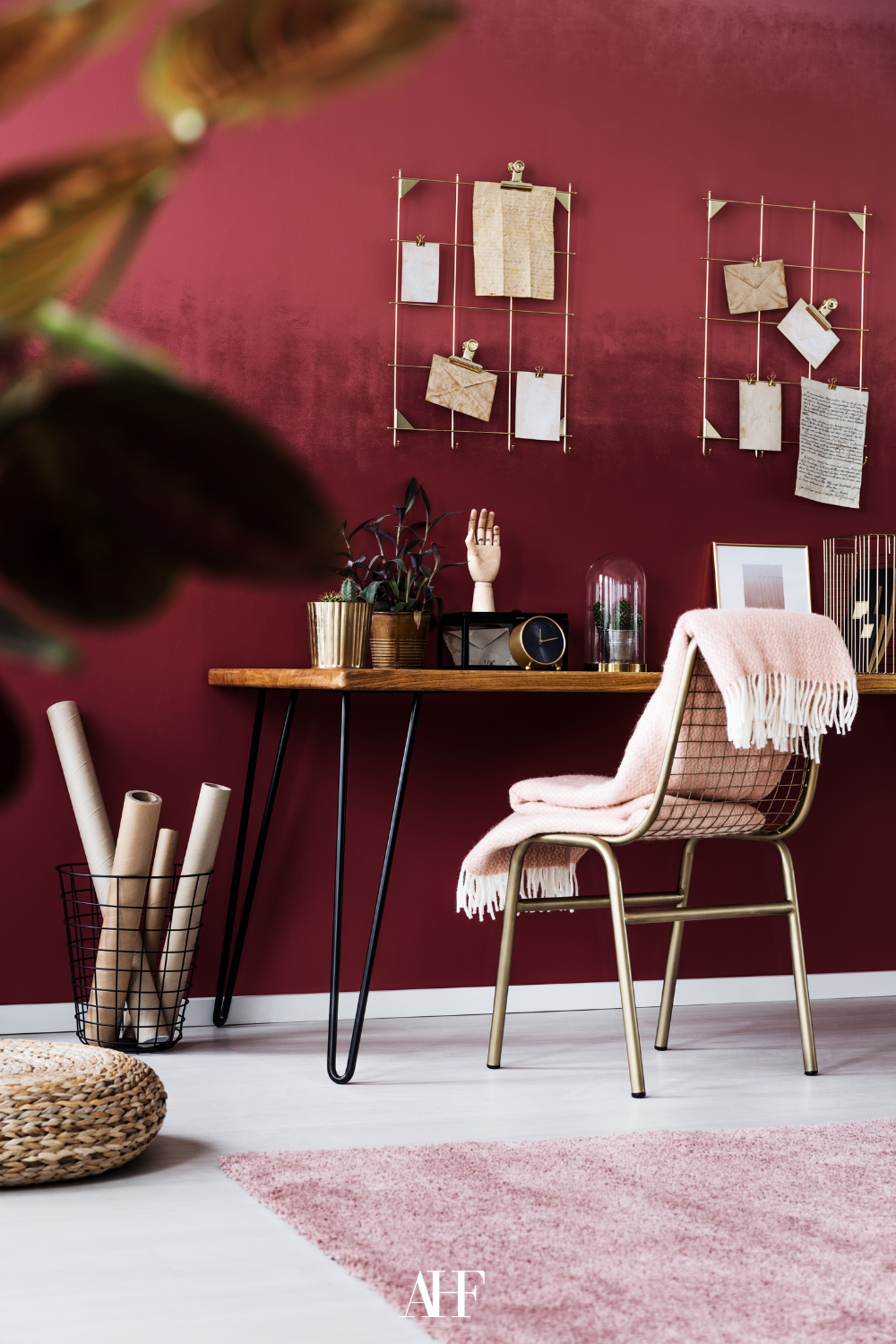 Cherry coded home with a large cherry red wall and a wooden dining table and some blankets. An office. 