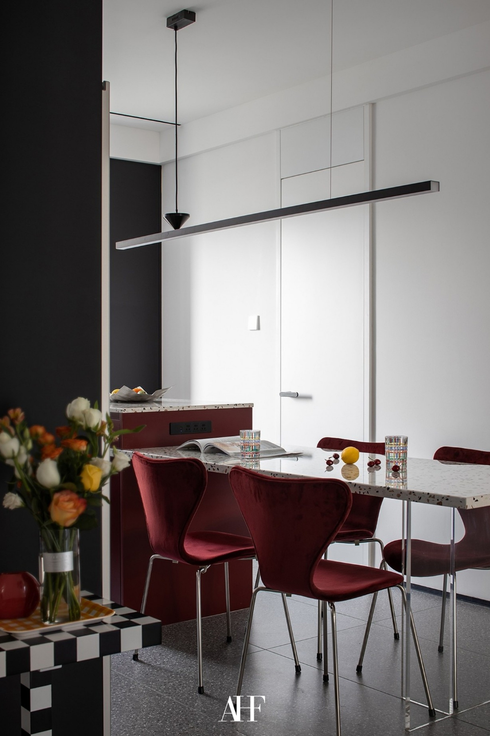 A cherry coded interior dining room with cherry red dining chairs and a stone dining table. 