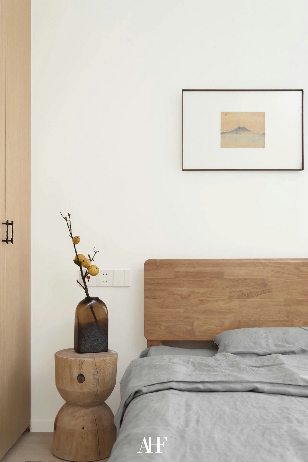 Beautiful japandi bedroom ideas with a wooden head board, a wooden bedside table and a neutral bedding. A wall art above the bed.