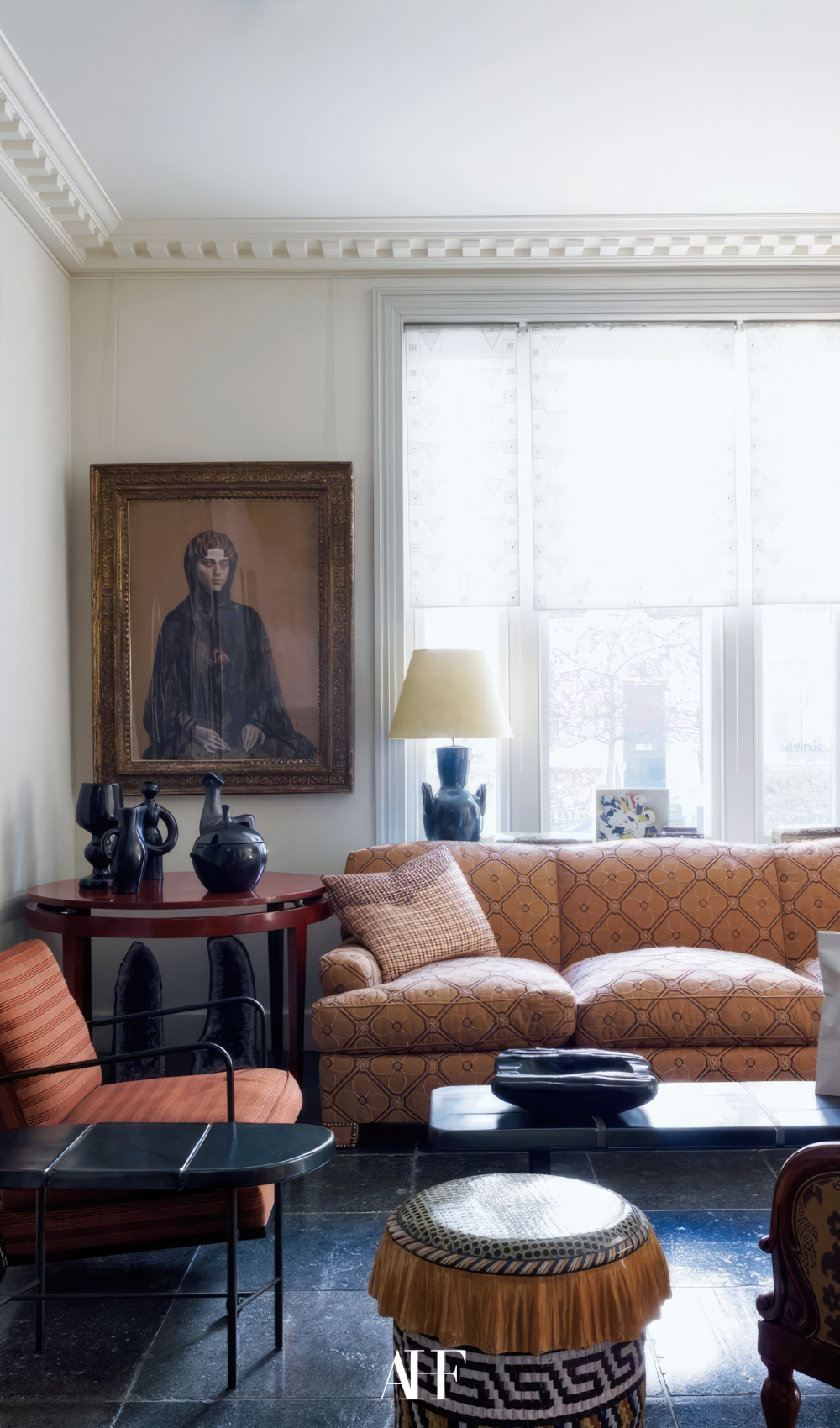 London townhouse interior design with a patterned sofa and armchair, victorian details, large windows behind the sofa.  