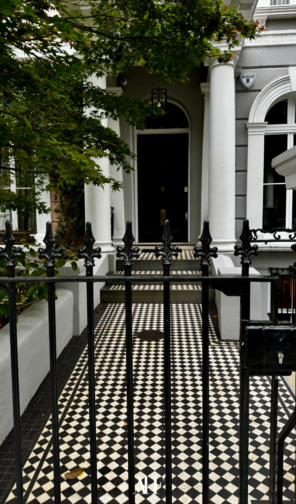 A London townhouse style entrance with checkered floors and a railing. 