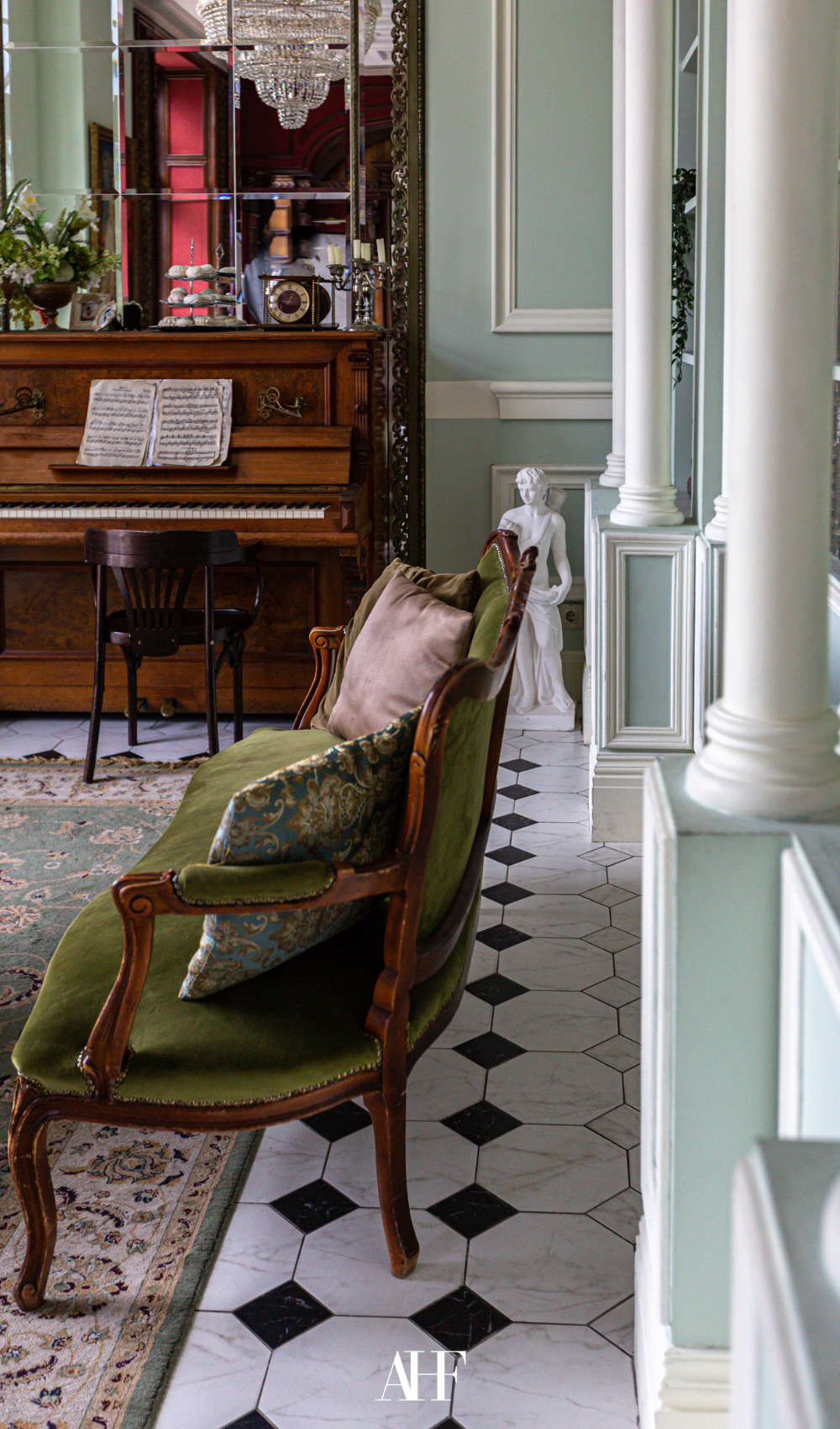 A London townhouse interior design with a checkered floor, a wooden piano and an antique sofa. 