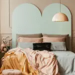A beautiful and colorful bedroom with a turqouise bed frame and a muted colorful bedding. Well decorated.