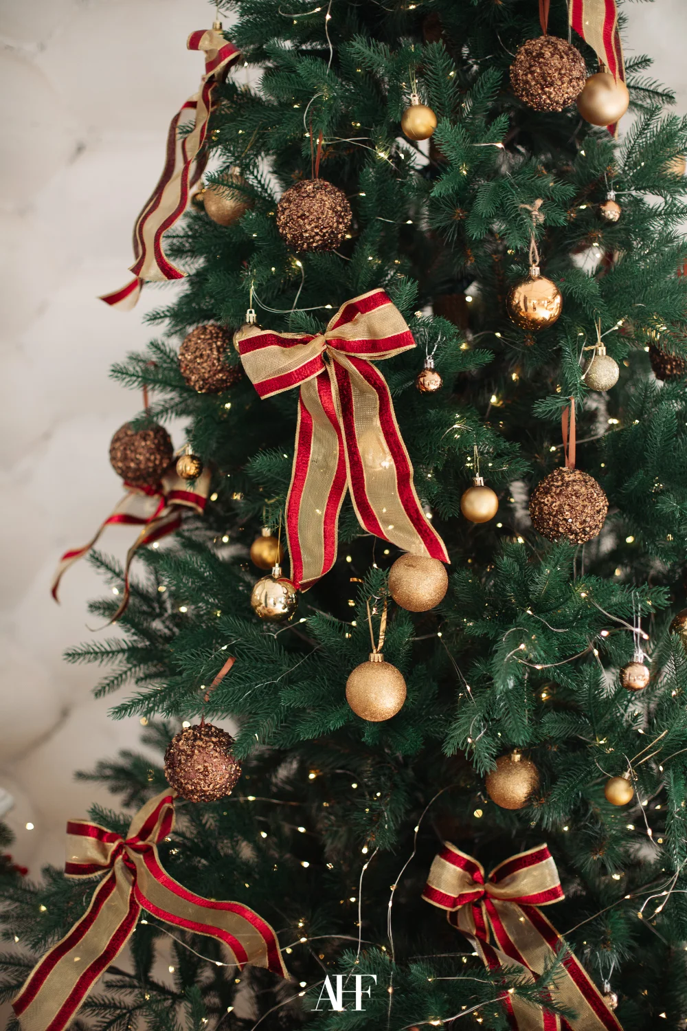 A closeup of a Ralph Lauren Christmas tree with golden ornament and bow ornament.
