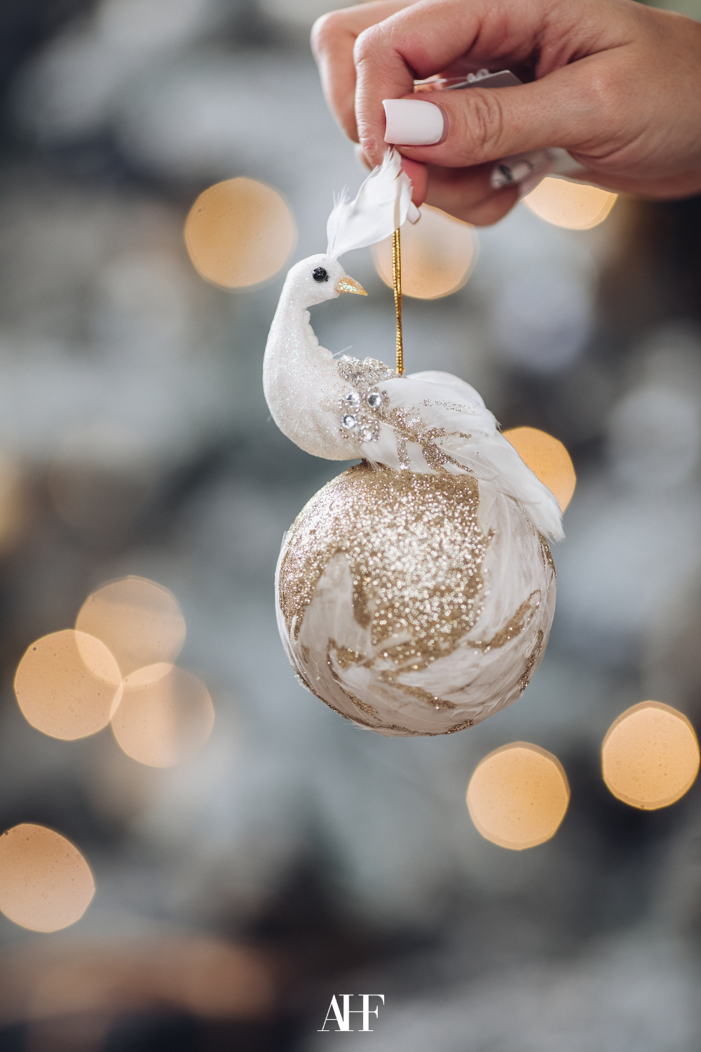 A handmade Christmas ball with a bird on it. A hand holding upp the decoration. 